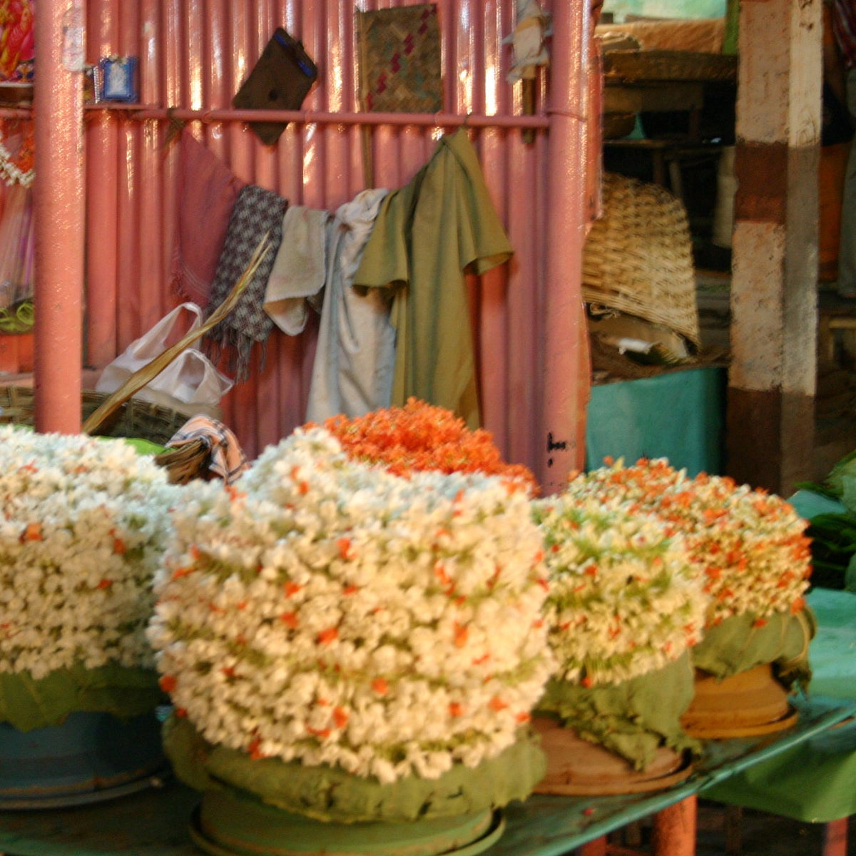Coiled strings of white jasmine dotted with orange kanakambaram at a market stall