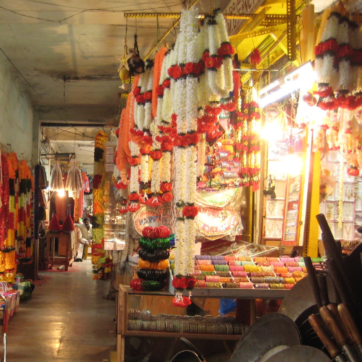 White flower garlands with red rose bands hanging in a garland shop