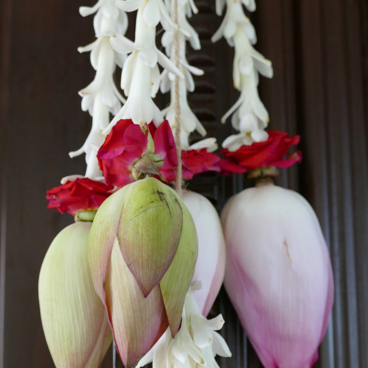 Close-up of white tuberose strands finished with red roses and pink lotus buds