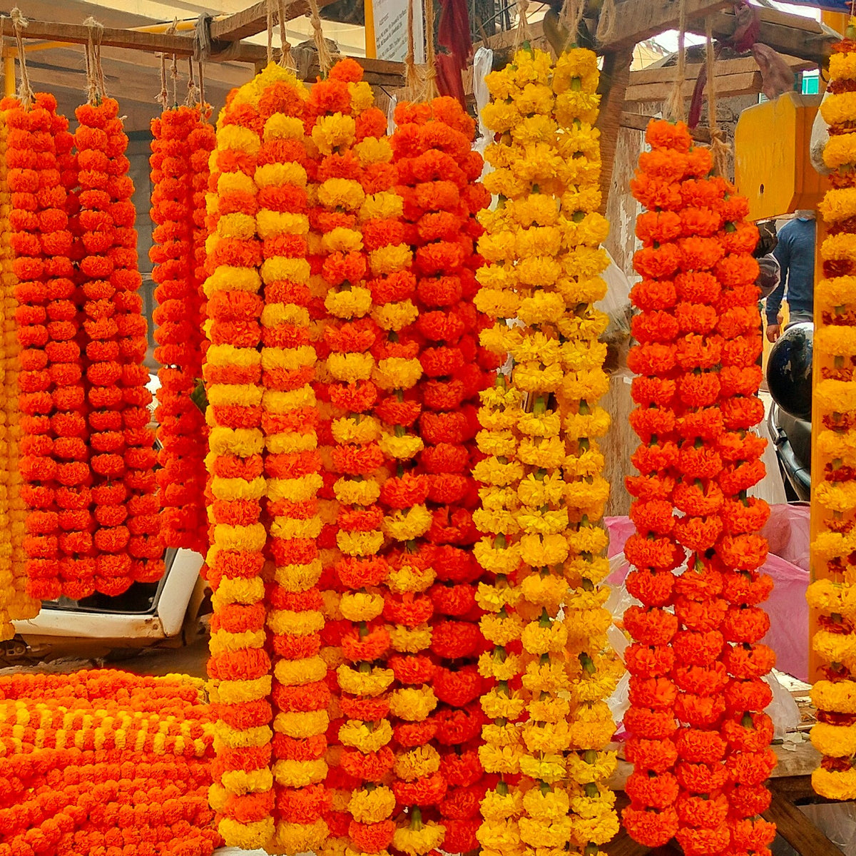 Yellow, orange and mixed marigold strings hanging at a roadside flower stall
