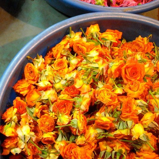 A tub of loose orange rose heads at a flower market