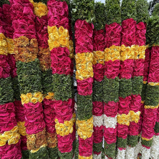 Several rose garlands hanging for sale at a flower market