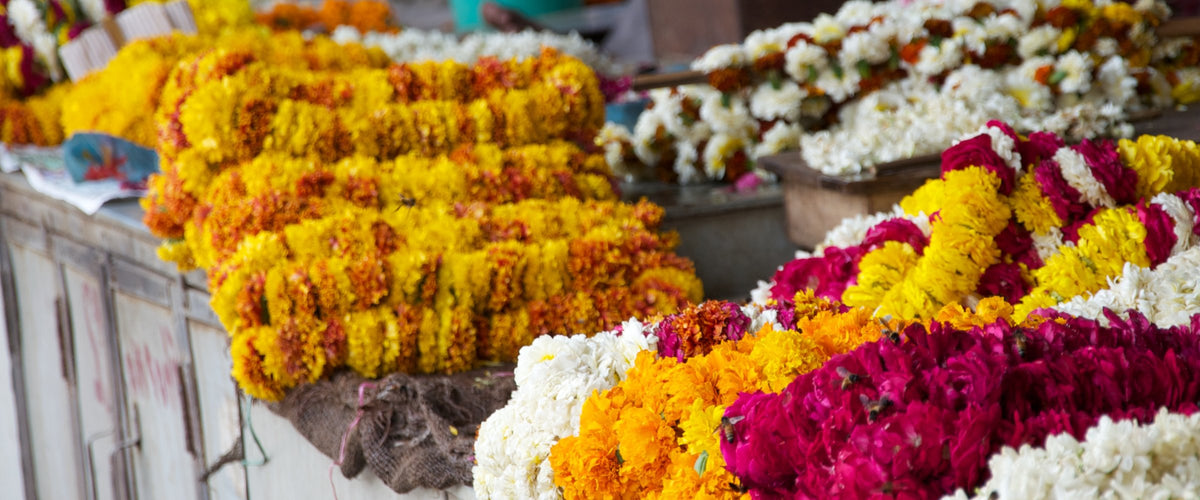 Marigold, white chrysanthemum and red rose garlands on a market stall